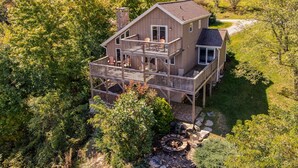 A two-story house with a balcony and a deck, surrounded by trees. - Aspen View - 3-story home with gorgeous views, a hot tub, and perfect location! (Blowing Rock)