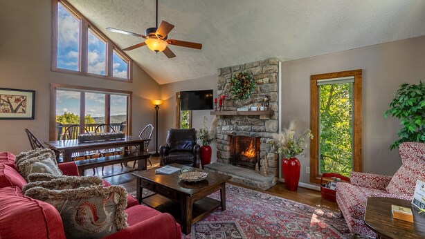 A cozy living room with a fireplace, a dining area, and a large window overlooking a scenic view. - Aspen View - 3-story home with gorgeous views, a hot tub, and perfect location! (Blowing Rock)