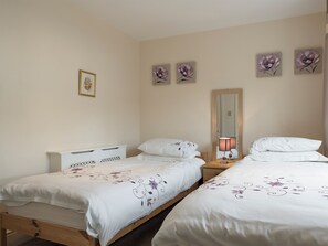 Une chambre avec deux lits, une table de chevet, une lampe et des motifs floraux décorant le mur.