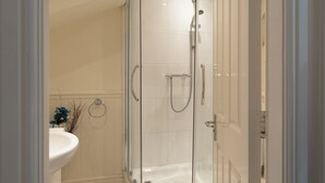 A modern bathroom with a glass-enclosed shower, a white sink, and a decorative vase with blue flowers. - 3 bedroom accommodation in Windermere (Windermere)