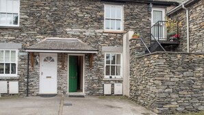 A stone building with a green door, white windows, and a small balcony with plants. - 3 bedroom accommodation in Windermere (Windermere)