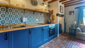 Une cuisine avec des armoires bleues, un plafond en bois et un pare-feu décoré.