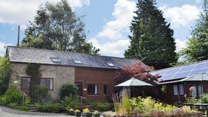 Un bâtiment de style rustique, avec des murs en pierre, un revêtement en bois et une allée gravillonnée.
