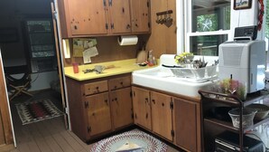 Une cuisine avec des meubles de rangement en bois, un évier blanc et une fenêtre.