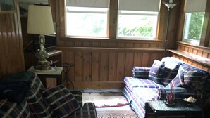 Une pièce chaleureuse avec un canapé à carreaux, un tapis à motifs et une fenêtre équipée de stores.