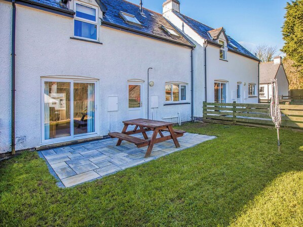 A house with a patio, a wooden table, and a grassy yard.