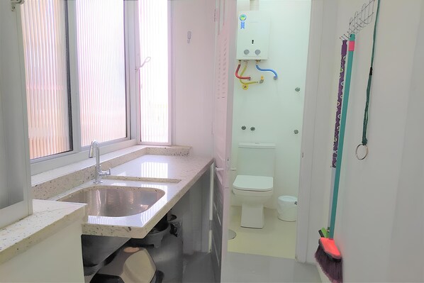 A small, clean bathroom with a sink, toilet, and window. - Apartamento Aluri (Porto Alegre)