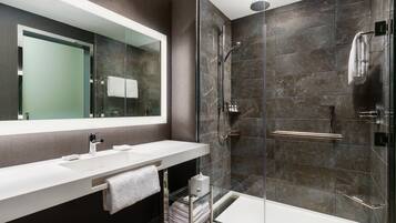 A modern bathroom with a glass-enclosed shower, a white sink, and a large mirror.