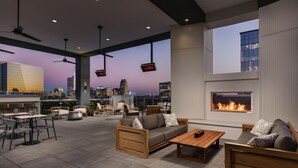 A rooftop lounge with outdoor seating, a fireplace, and a city view at dusk. - AC Hotel by Marriott Raleigh Downtown (Raleigh)