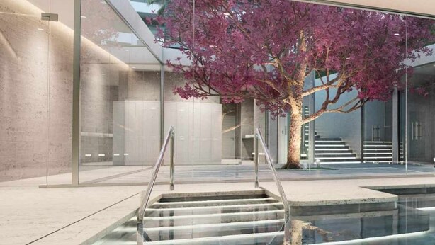 A modern indoor pool area with glass walls, a staircase leading to a higher level, and a tree with pink flowers. - Spectacular beachfront panoramic terrace (Torremolinos)