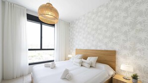 A neatly made bed with white linens, a wooden headboard, and a bedside lamp on a nightstand. - Spectacular beachfront panoramic terrace (Torremolinos)