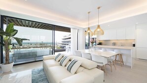 A modern living room with a sofa, dining table, and kitchen area. - Spectacular beachfront panoramic terrace (Torremolinos)