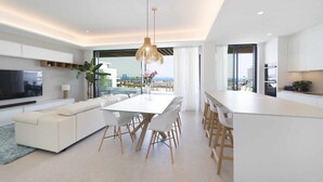 A modern living room with a sofa, dining table, and chairs, a TV, and a large window with a view. - Spectacular beachfront panoramic terrace (Torremolinos)