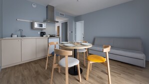 A compact living space with a kitchenette, dining area, and a sofa. - The Originals City, Hôtel Le Relais des Deux Mers, Marmande Sud (Samazan)