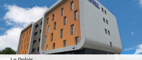 A modern hotel building with a curved facade, multiple windows, and a prominent 'HOTEL' sign.