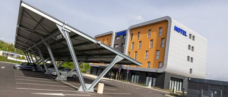 A modern hotel with a covered parking area and a multi-story building with a prominent 'HOTEL' sign.