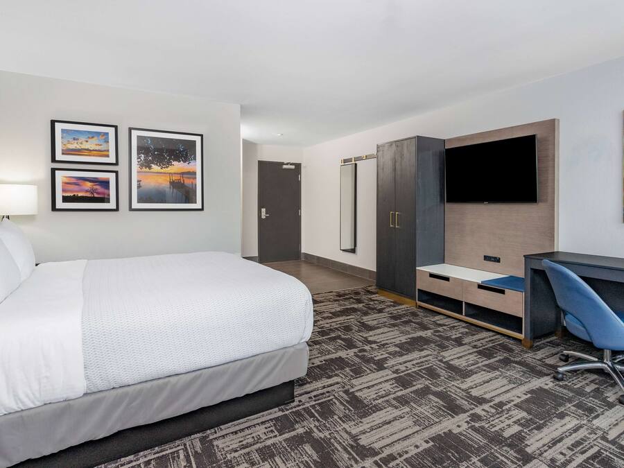 Quarto de hotel com cama, escrivaninha, televisão e obras de arte nas paredes.