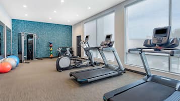 A modern gym with treadmills, exercise bikes, and a rowing machine.