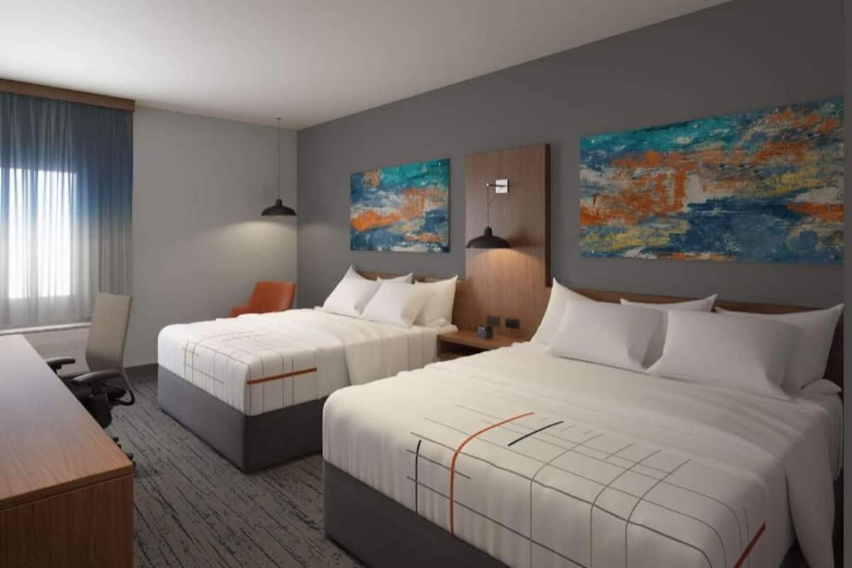 Ein Hotelzimmer mit zwei Betten, einem Schreibtisch und Bildern an den Wänden.