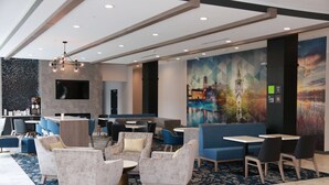 Un hall de hotel con zonas de estar, un televisor y un mural.