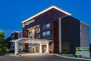 Een modern hotel met een opvallend 'La Quinta by Wyndham' bord, bestaande uit een meerhoog gebouw met een overdekte ingang en een goed verlichte gevel.