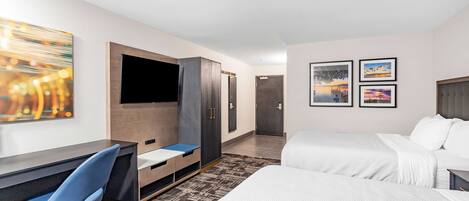 Una habitación de hotel con cama, escritorio con silla, televisor y obras de arte en las paredes.