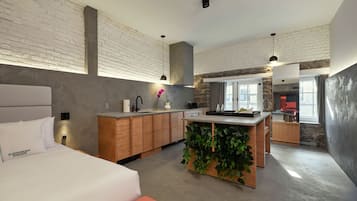 Una habitación de hotel moderna con una cama grande, una pequeña cocina y un comedor.