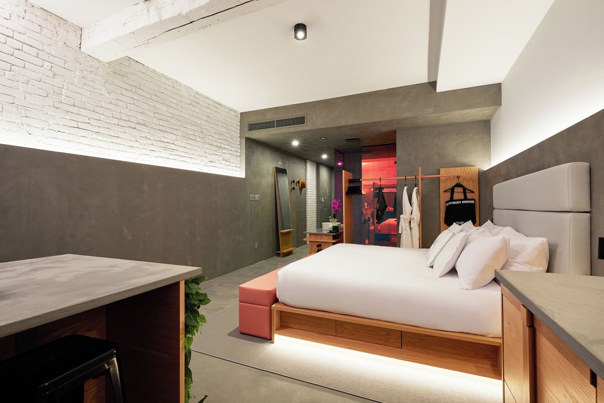 Un dormitorio moderno con una cama grande, un escritorio y una pequeña zona de estar.