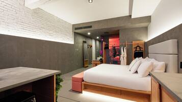 A modern bedroom with a large bed, a desk, and a small seating area.
