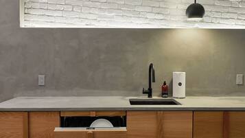 A modern kitchen with a white brick backsplash, a black faucet, and a built-in dishwasher.