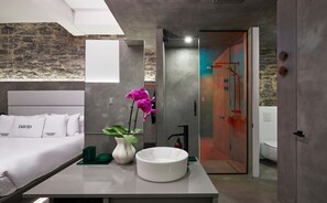 Une salle de bain moderne avec un grand miroir, un lavabo blanc et un espace douche.