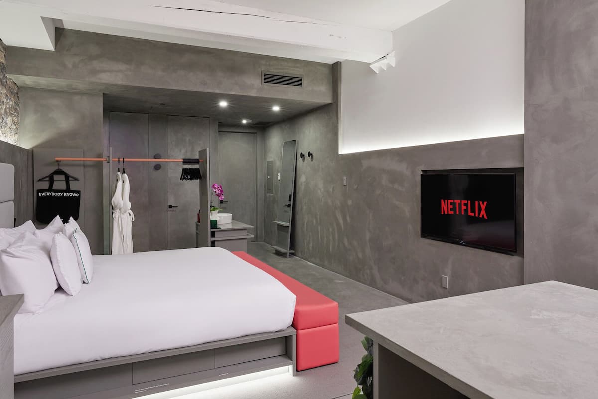Un dormitorio moderno con una cama, televisión y baño.