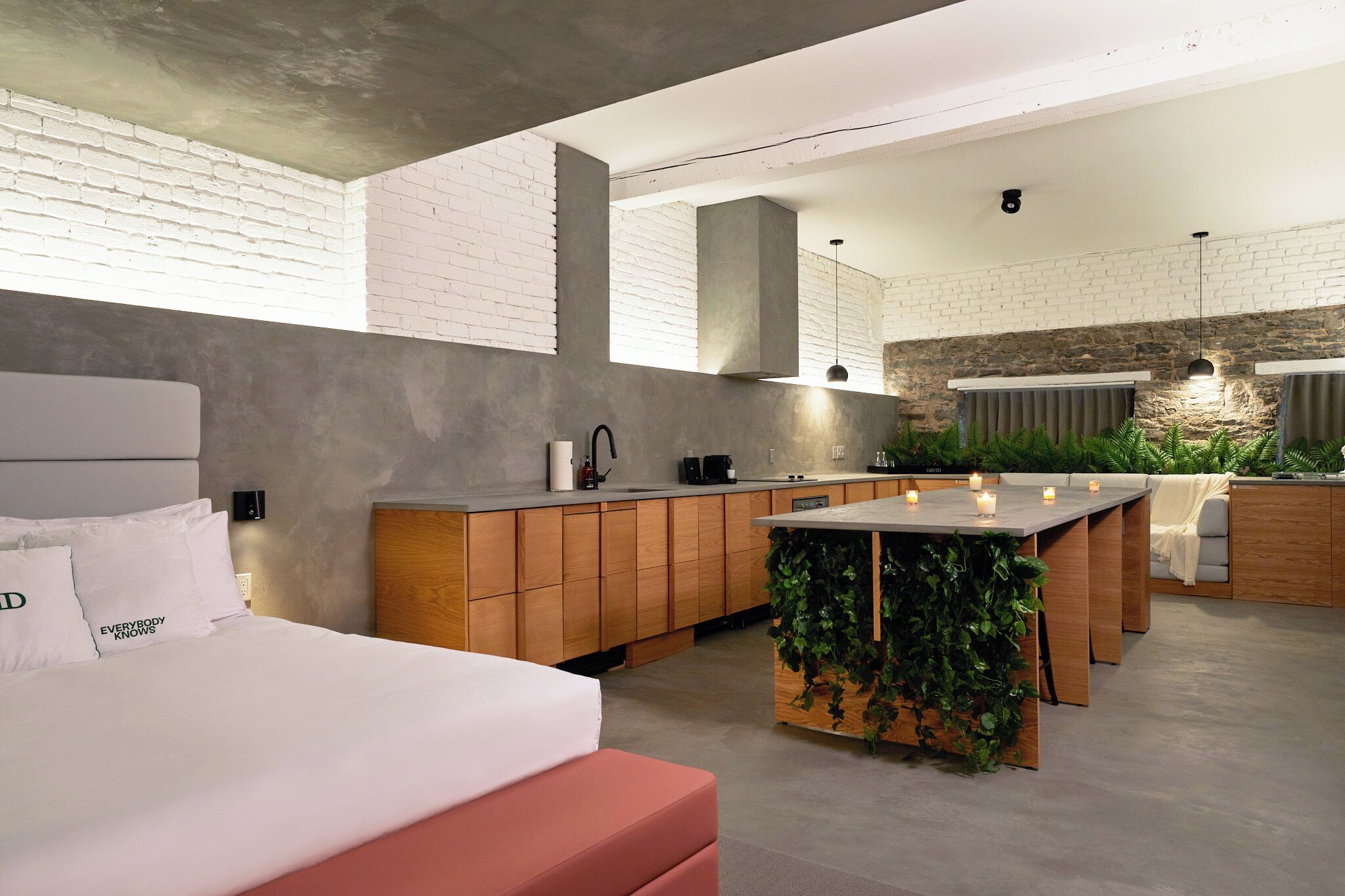 Une chambre moderne avec un grand lit, une table de chevet en bois et une petite table avec des bougies.