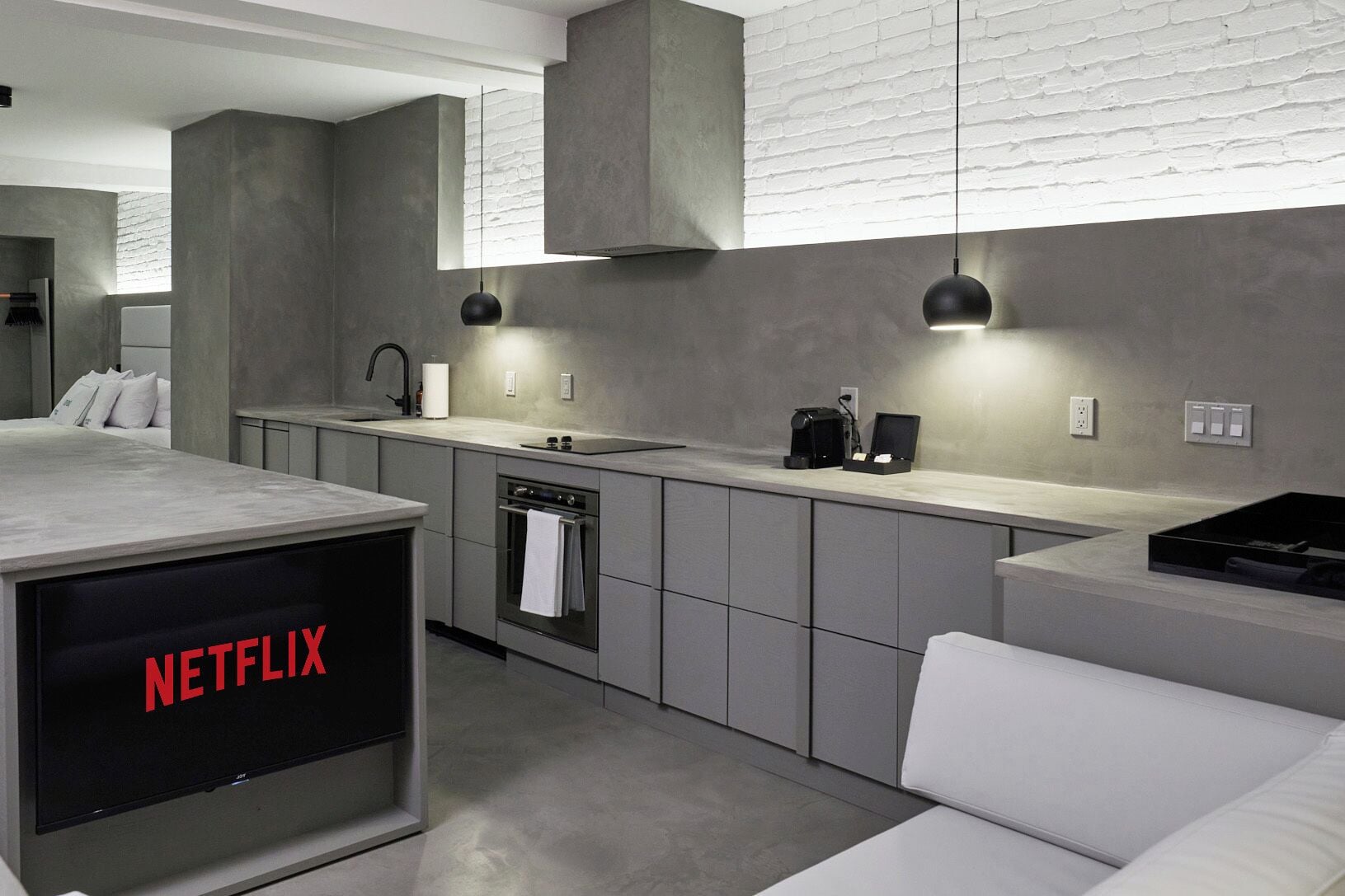 A modern kitchen with grey cabinetry, a built-in oven, a sink, and a coffee maker.