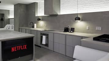 A modern kitchen with grey cabinetry, a built-in oven, a sink, and a coffee maker.