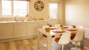 Une cuisine avec une table à manger, des chaises et une horloge au mur.
