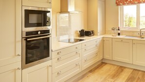 Une cuisine moderne dotée d’appareils électroménagers en acier inoxydable, de meubles blancs et d’un plancher en bois.
