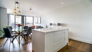 Una cocina moderna con una isla central, comedor con sillas y un ventanal con vista a la ciudad.