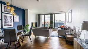 Una sala de estar moderna con comedor, ventanas grandes y vista a la ciudad.