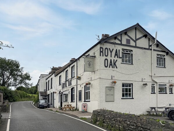 Un edificio con la señalización 'ROYAL OAK', un muro de piedra y un coche estacionado.