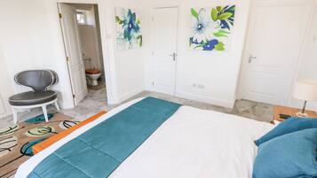 Quarto com uma cama, uma cadeira, uma porta e uma parede com arte floral.