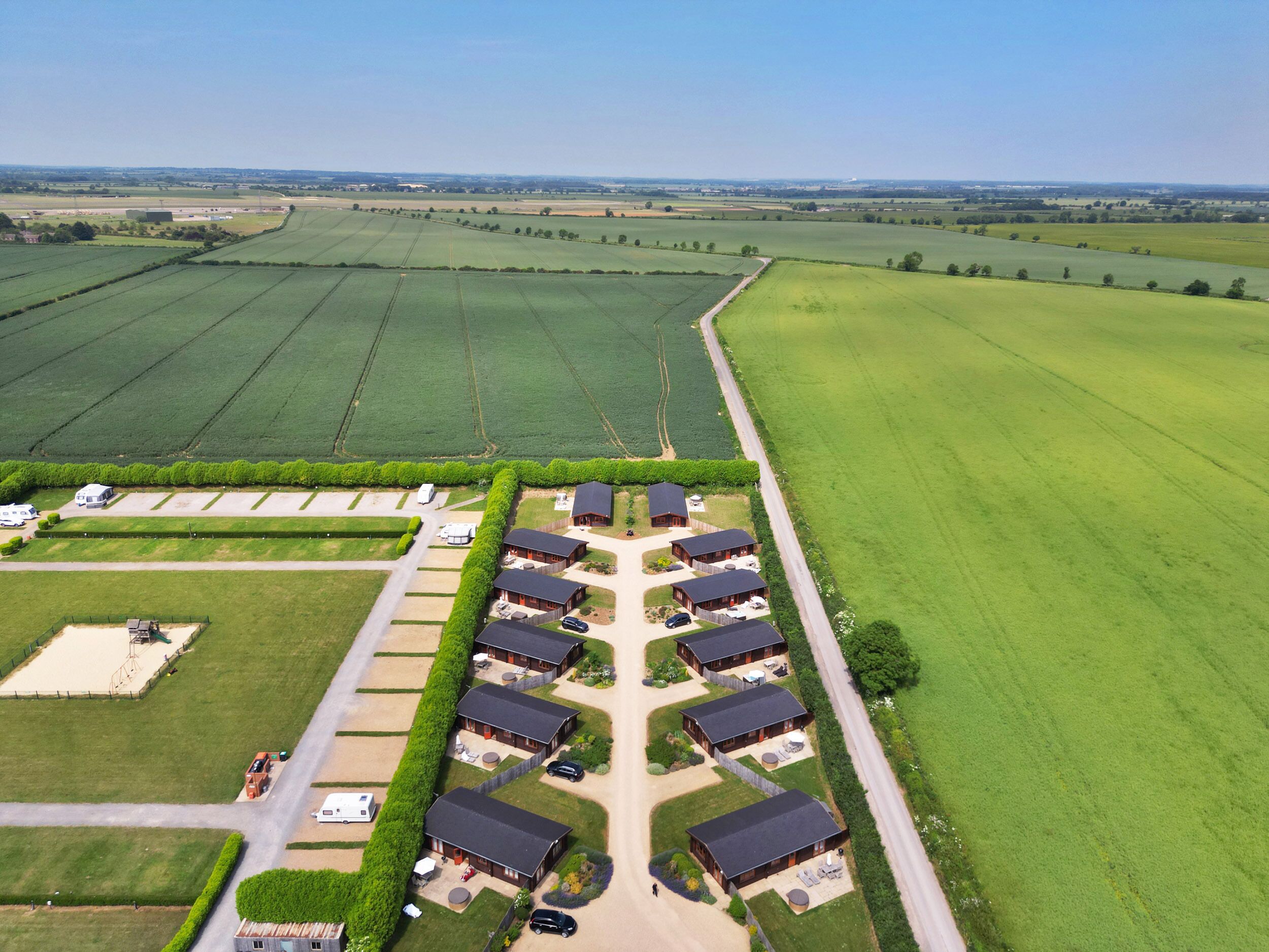 Vista aérea de una propiedad rural con varias construcciones, un área de estacionamiento y campos circundantes.