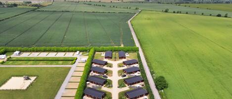 Vista aérea de una propiedad rural con varias construcciones, un área de estacionamiento y campos circundantes.