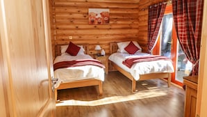 Une chambre dans un chalet en bois, avec deux lits, une table de chevet, une lampe et un tableau au mur.