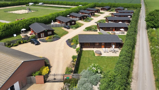 Un ensemble de logements ruraux comprenant plusieurs chalets, une route principale et des champs environnants.