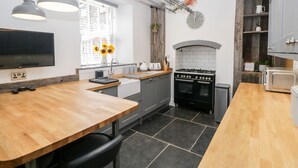 Una cocina moderna con una mesa de madera, piso de baldosas blanco y negro y horno empotrado.