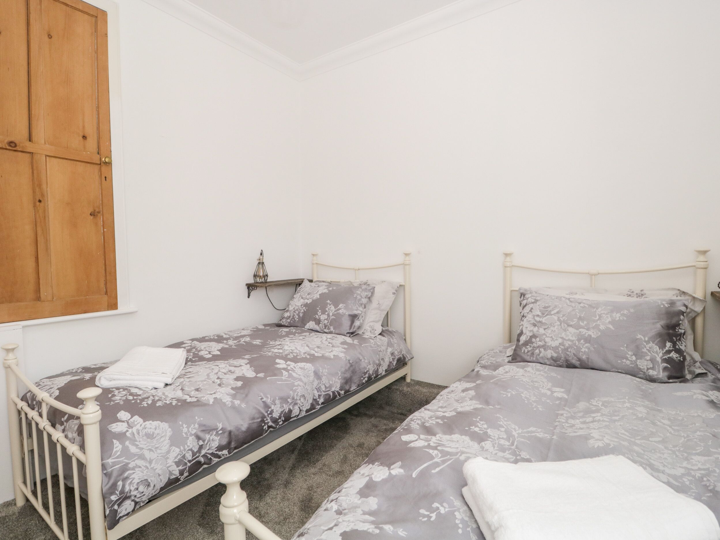 A bedroom with two single beds, each with floral bedding and a white headboard.