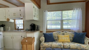A cozy RV interior with a kitchenette, a sofa with floral upholstery, and a gray ottoman. - Tiny Toot - “On Deep Creek” Bryson City, NC  (Bryson City)