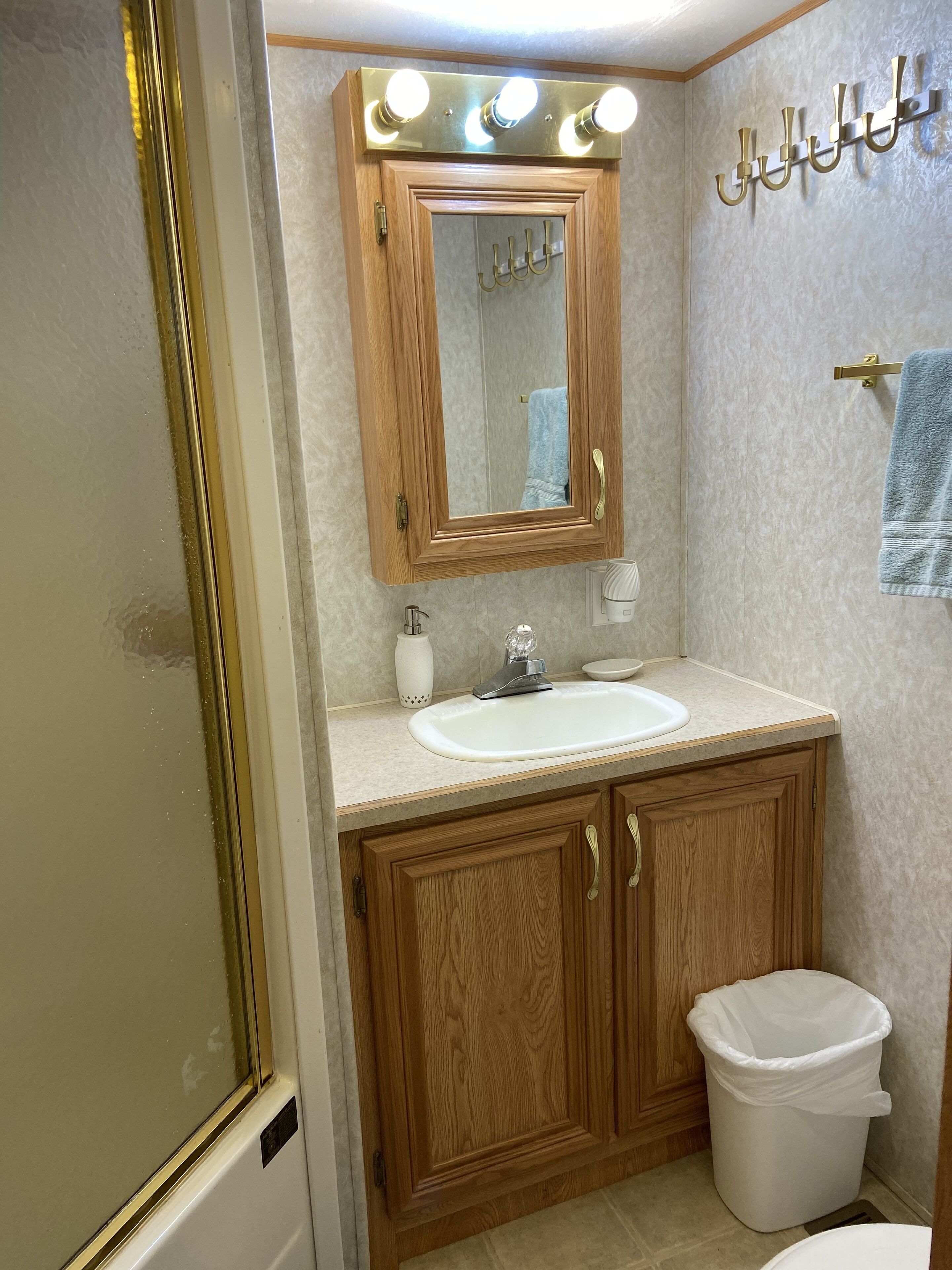 A bathroom with a wooden vanity, a sink, a mirror, and a towel rack.