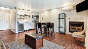 Una cocina moderna con comedor, chimenea y sala de estar con sofá y reposapiés.